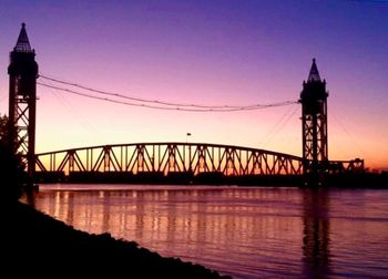 Suspension bridge over river at sunset