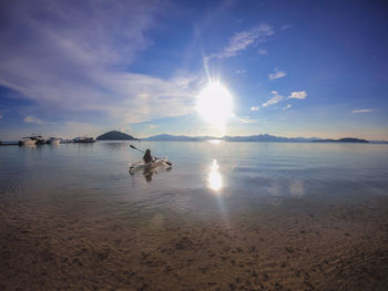 Woman kayaking in sea against sky