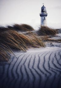 Lighthouse on snow covered land against sky