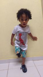 Portrait of cute girl standing against wall