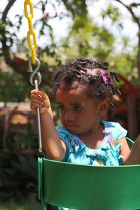 Close-up of girl looking away while sitting on swing