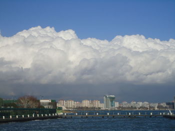 Sea by buildings against sky in city