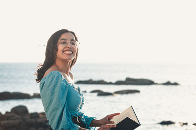 Portrait of young woman using phone on beach