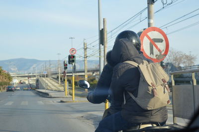 Rear view of couple sitting on motorcycle at road