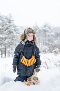 Russian boy with bagels around his neck and a string bag of tangerines outside in winter