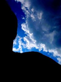 Low angle view of silhouette mountain against blue sky