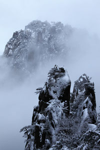 Rock formation on snow covered mountain against sky