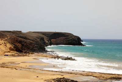 Scenic view of rocks on beach against clear sky
