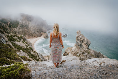 Woman standing on cliff against sea