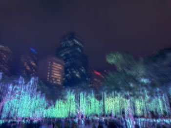 Illuminated cityscape against sky at night