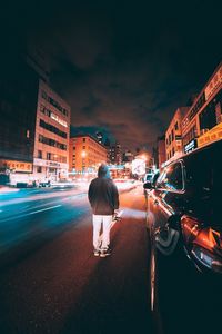 Rear view of man standing on street at night