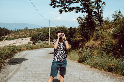 Full length of woman standing on road against trees