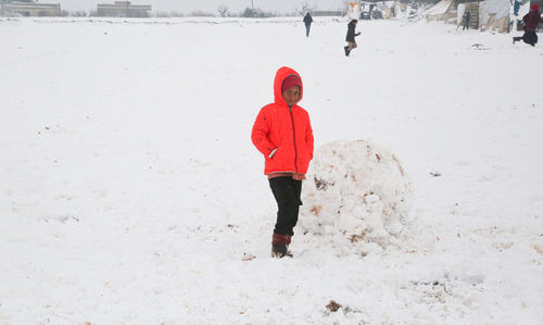 A syrian refugee child at the door of his snow covered tent.