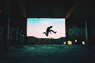 Silhouette man jumping on built structure