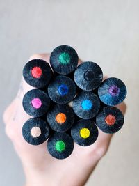 Close-up of hand holding multi colored pencils over white background