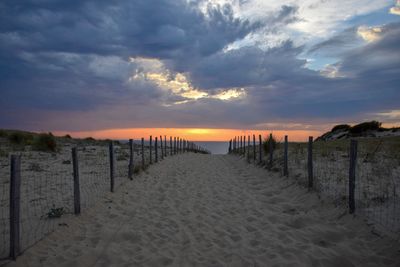 Wooden posts on beach against sky during sunset