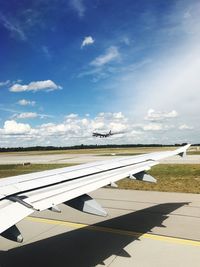 Airplane flying over airport runway against sky