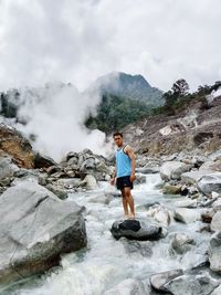 Rear view of woman standing against waterfall