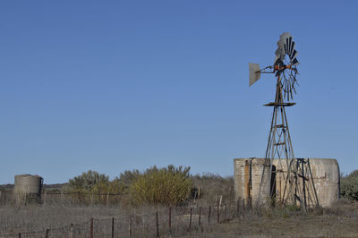 Low angle view of traditional windmill on field against clear sky