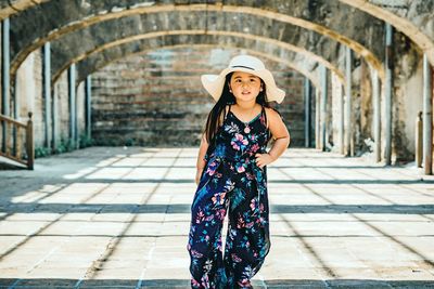 Portrait of a smiling young woman standing against brick wall