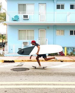 Side view of man skateboarding on road against building