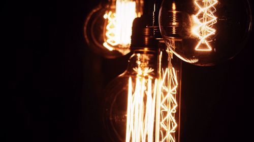 Cropped image of illuminated light bulbs against black background