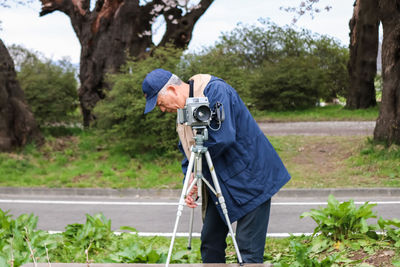 Man holding umbrella standing by trees