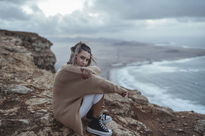 Portrait of young woman standing on mountain against sky