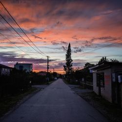 Road amidst buildings against sky during sunset