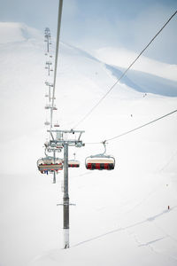 An open-air lift that goes to the top of the mountain for downhill skiing. sunny day surrounded by