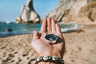 Close-up of hand holding navigational compass at beach