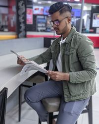 Young man looking away while sitting on paper