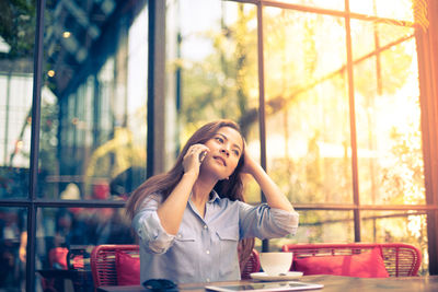 Young woman talking on smart phone in cafe