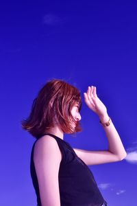Side view of woman against blue sky