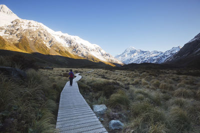 Rear view of man standing on mountain against sky