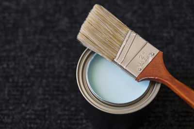 Close-up of paintbrush on paint can at table