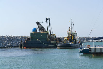 Fishing boat at harbor against clear sky