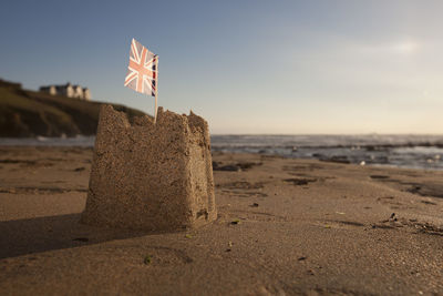 Close-up of flag on beach against sky