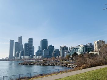 Modern buildings by river against sky in city