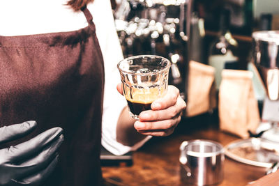 Midsection of woman holding wine glass on table