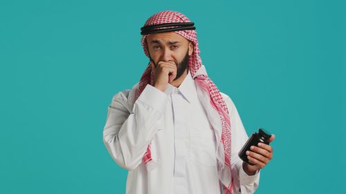 Young woman using mobile phone against blue background