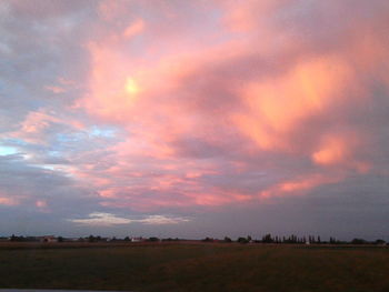 Scenic view of dramatic sky over land during sunset