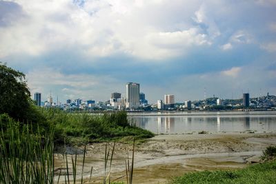 Scenic view of river by buildings against sky