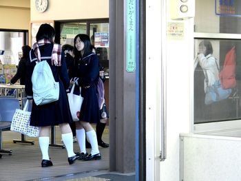 Rear view of people standing against window