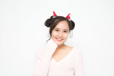 Portrait of young woman standing against white background