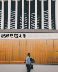 Full length of man standing on railing against building