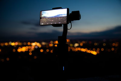 Mobile phone in city against sky at night