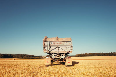 Hay bales on cart at farm against clear sky