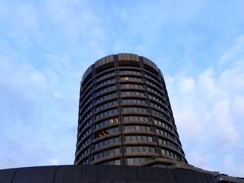 Low angle view of modern building against cloudy sky