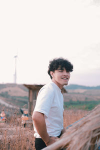 Man smiling on field against sky